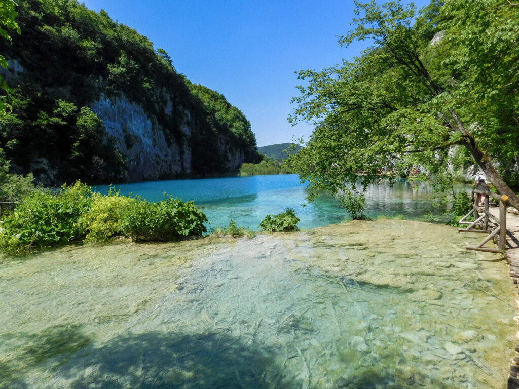 image of Plitvice national park showing blue skies, blue water, and green trees