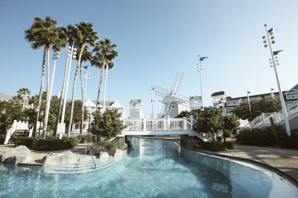 Part of Stormalong Bay, a large lazy river with a white bridge and a windmill flanked by palm trees.