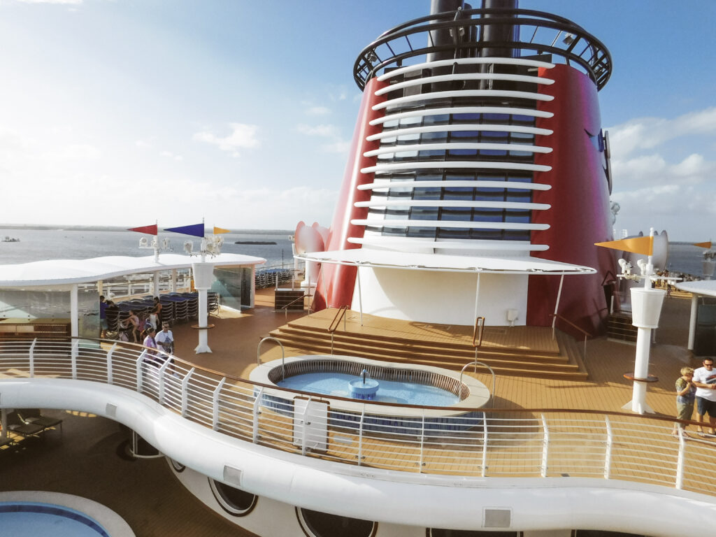 The deck of a cruise ship with a small fountain and pool.