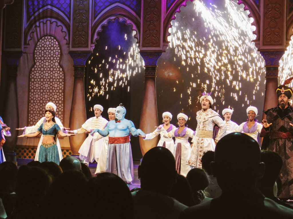 Costumed actors in Aladdin singing as they perform a live show.